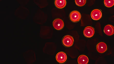 Overhead-Aufnahme-Romantisch-Angezündeter-Roter-Kerzen-Auf-Einem-Mit-Rosenblättern-Bedeckten-Hintergrund-Mit-Kopierraum